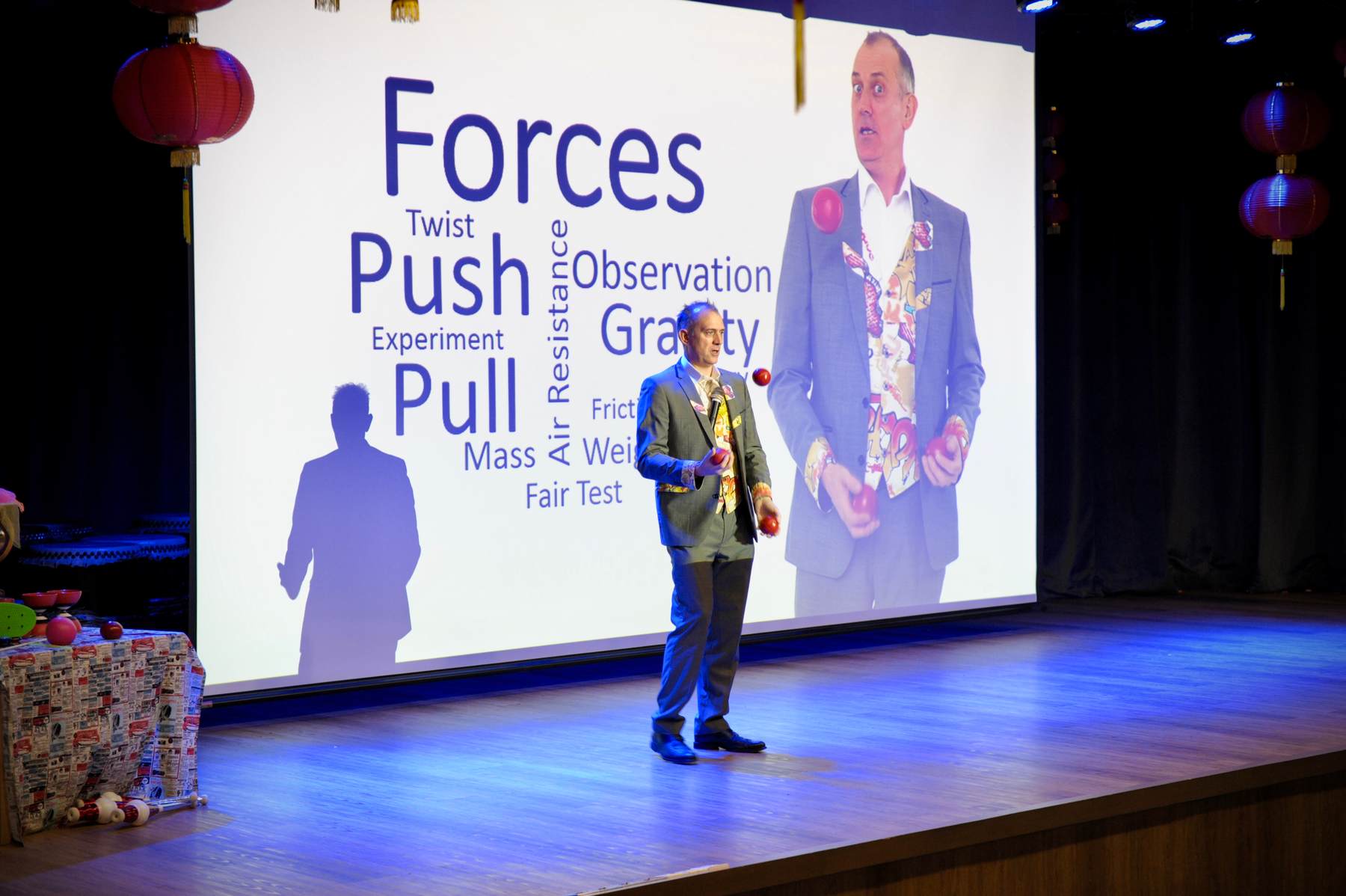 Dr Ken Juggling in front of a giant screen at St Josephs school, Kuala Lumpur, Malaysia Dr Ken juggling 3 bean bags whilst presenting in front of a large screen of forces keywords.