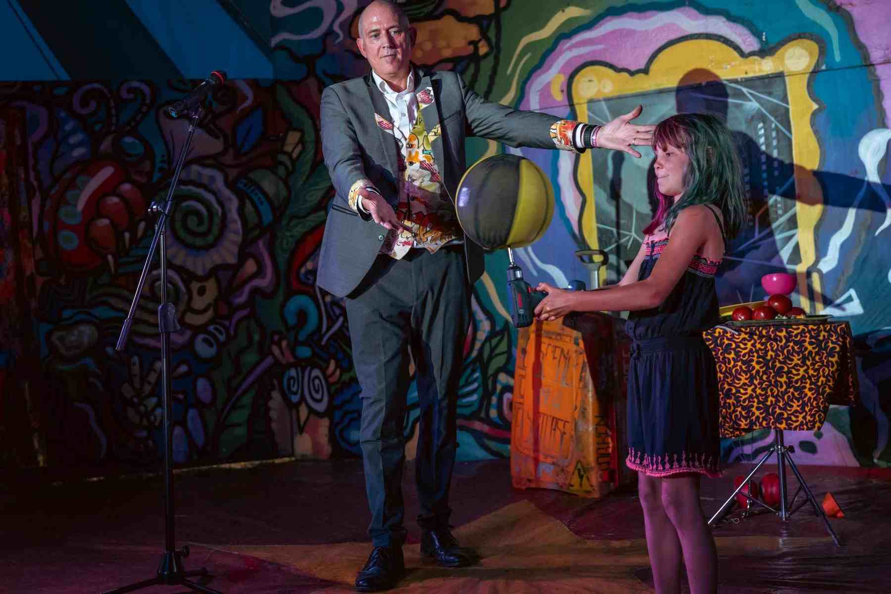 Dr Kens volunteer balances a spinning Ball on a Drill at the Maui Waui Festival A 10 year old shows Dr Ken how's it's down by spinning a Basketball on a power drill