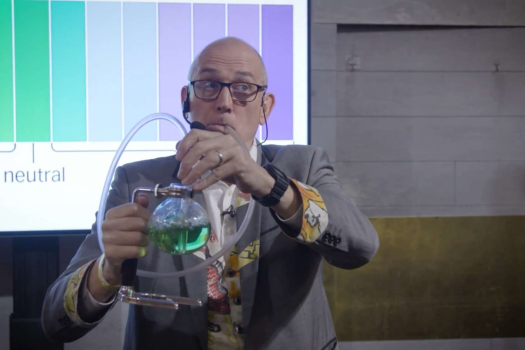 CO2 and changes in Ocean Acidity Dr Ken breaths out of a clear plastic tube pipe into a bubbling flask of green coloured water (a solution of Universal Indicator).