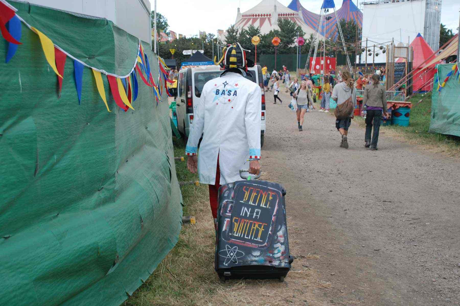 Dr Ken is outstanding in a field dressed in his BASA outfit with a suitcase spray painted with the words "Science in a Suitcase".