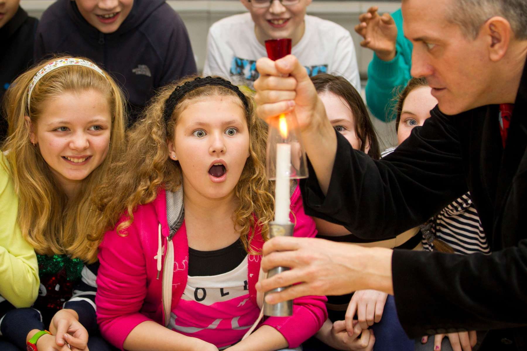 Amazed students observe a as a glass is placed above it.