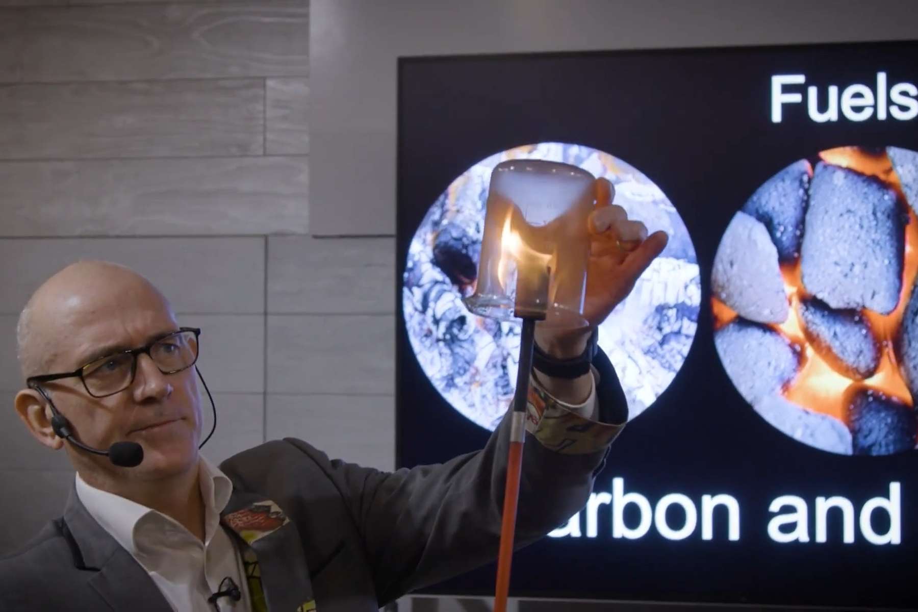 Dr Ken covers a burning fire torch with a glass beaker.