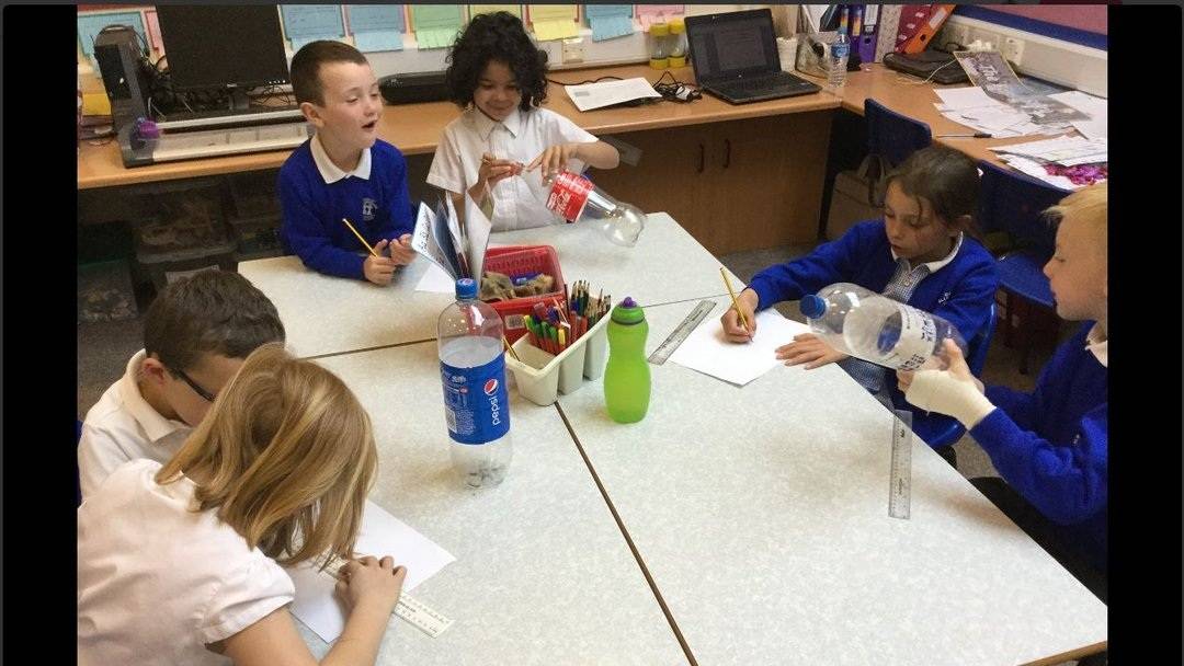 Small groups of School pupils discuss their designs for a wind turbine recycling activity.