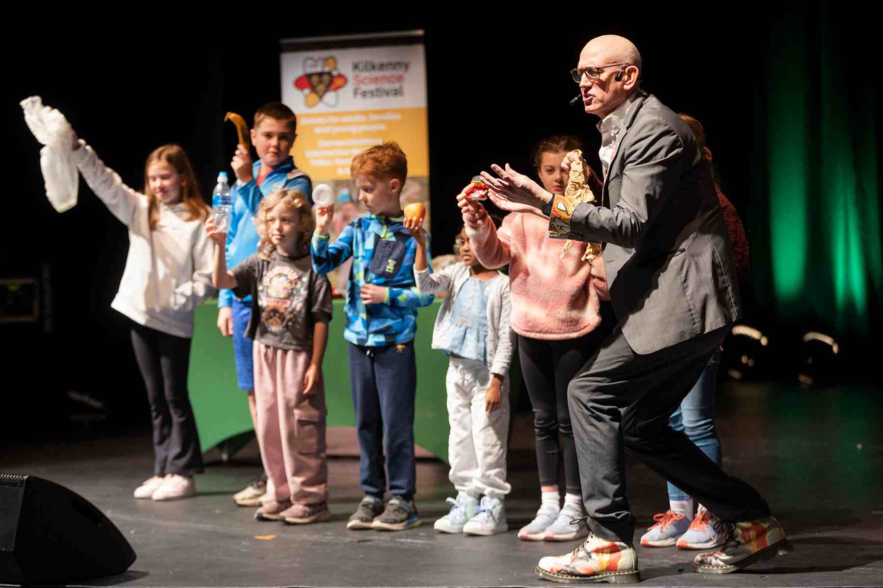 Young volunteers on staging playing a sorting decomposing rubbish game